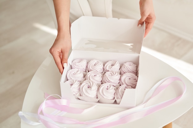 Konditormädchen, das rosa Marshmallows in einer weißen Geschenkbox hält