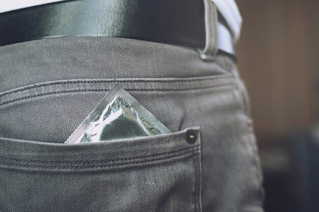 Kondom gebrauchsfertig in Pocket Jeans Hosen, geben Safe-Sex-Konzept auf dem Bett Verhindern Sie Infektionen und Verhütungsmittel kontrollieren die Geburtenrate oder sichere Prophylaxe. Welt-AIDS-Tag,