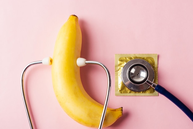 Kondom in Packung, Banane und Arztstethoskop