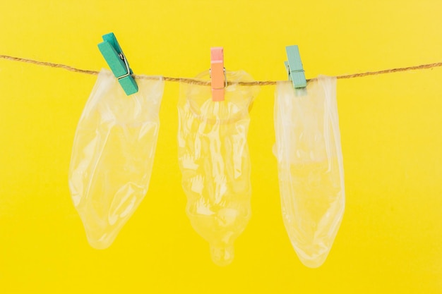 Kondome hängen an einem Seil vor gelbem Hintergrund Safer-Sex-Konzept