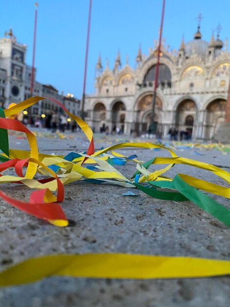 Konfetti und farbiges Papier auf dem Boden des verlassenen Markusplatzes während des Karnevals und der Krise COVID19 Basilika San Marco im Hintergrund