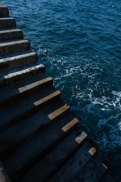 Konkrete Stufen führen an einem sonnigen Tag zum Meer Minimalistisches Foto mit Licht und Schatten