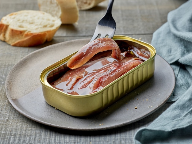 Konservierte Sardellenfilets und Baguettescheiben auf Holzküchentisch