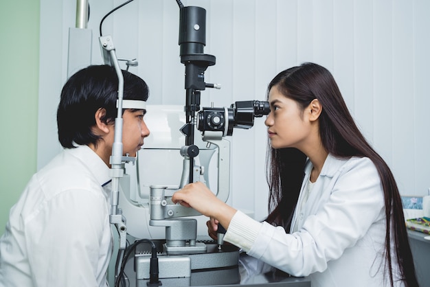Konsultation mit einem Augenarzt. Junger asiatischer Mann und Frau Arzt