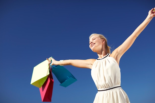 Konsum-, Verkaufs- und Personenkonzept - lächelnde Frau mit aufsteigenden Händen der Einkaufstasche