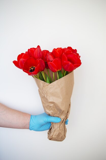 Kontaktlose Lieferung eines Straußes schöner roter Tulpen,