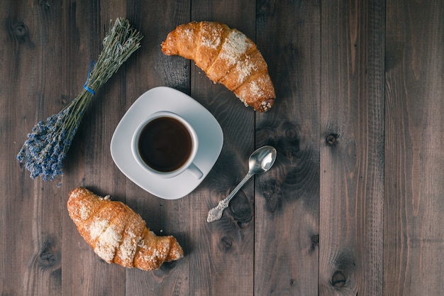 Kontinentaler Frühstückstisch - ein Paar Croissants. Rustikaler Holztisch mit Platz für Text. Draufsicht.