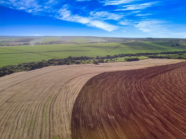 Kontrast im Feld zwischen gepflügtem Land, das zum Anpflanzen bereit ist, und rohem Land.