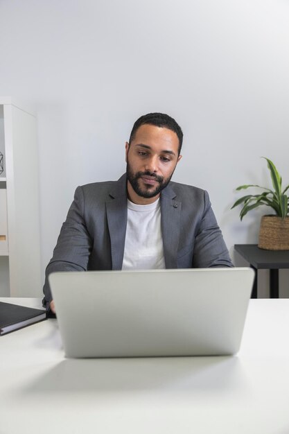 Konzentration und Fokus. Nachdenklicher junger afroamerikanischer Unternehmer, Geschäftsmann, der mit Laptop zu Hause arbeitet. Vertikales Bild. Platz kopieren. Geschäftskonzept. Technologiekonzept.