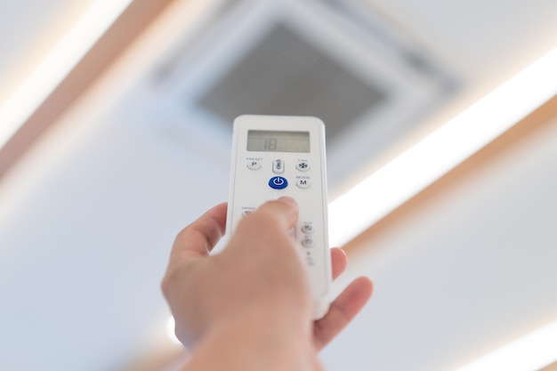 Foto konzentrieren sie sich auf den netzschalter der fernbedienung der klimaanlage, um sie an der decke des seminarsaals zu öffnen und auszuschalten.