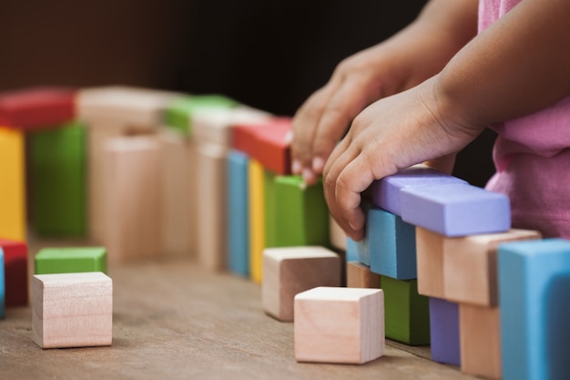 Konzentrieren sie sich auf die hand des kindes, die mit bunten holzklötzen im weinlesefarbton spielt