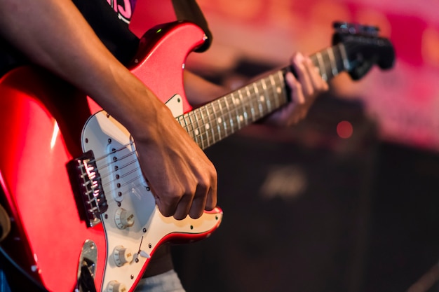 Konzentrieren Sie sich auf die Hand, die die elektrische Holzgitarre auf der Bühne spielt.