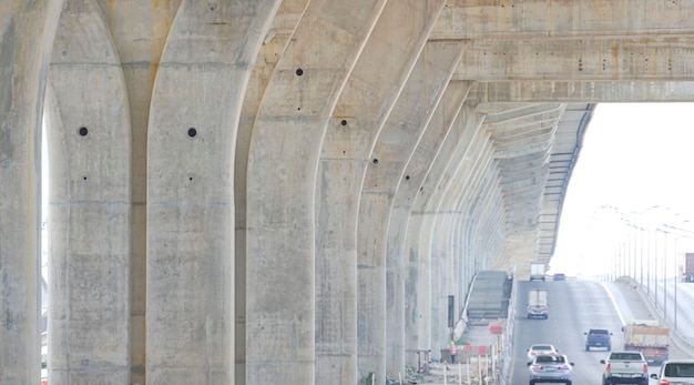 Konzentrieren Sie sich auf die im Bau befindliche Überführungsfundamentstruktur über der Brücke mit vorbeifahrendem Fahrzeug