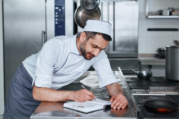 Konzentrieren Sie sich auf die Lebensmittelsicherheit glücklicher Küchenchef, der in der gewerblichen Küche steht