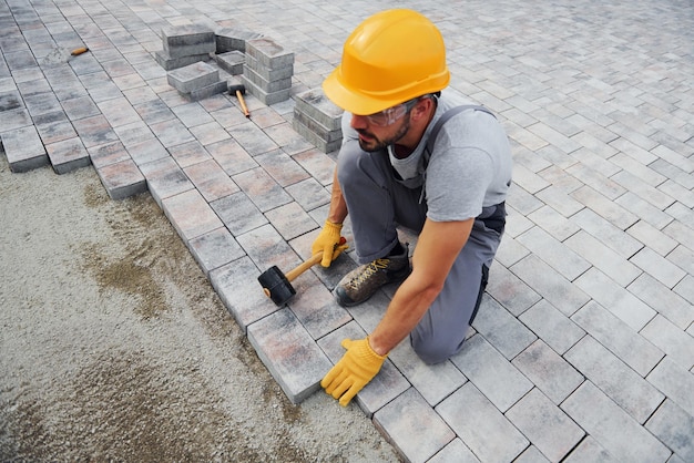 Konzentriert bei der Arbeit Mann in gelber Uniform hat Arbeit mit Pflaster