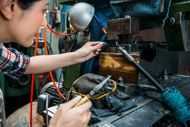 konzentrierte drehmaschine, die eine zange hält, um kleine komponenten in der maschine einzustellen, wenn sie in der fräsmaschinenfabrik arbeitet.