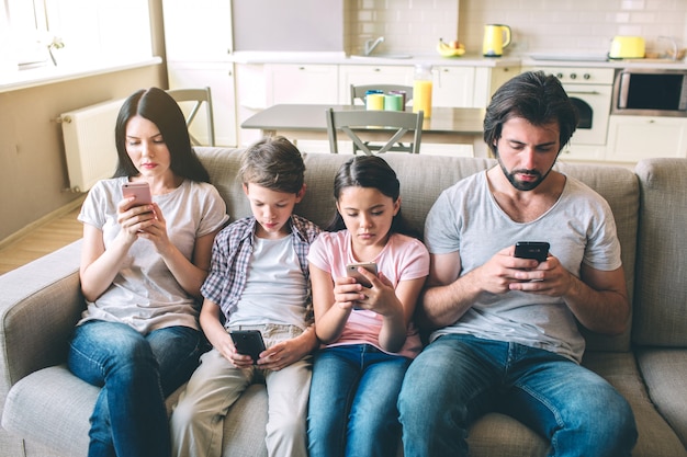 Konzentrierte Familienmitglieder sitzen zusammen auf einem Sofa