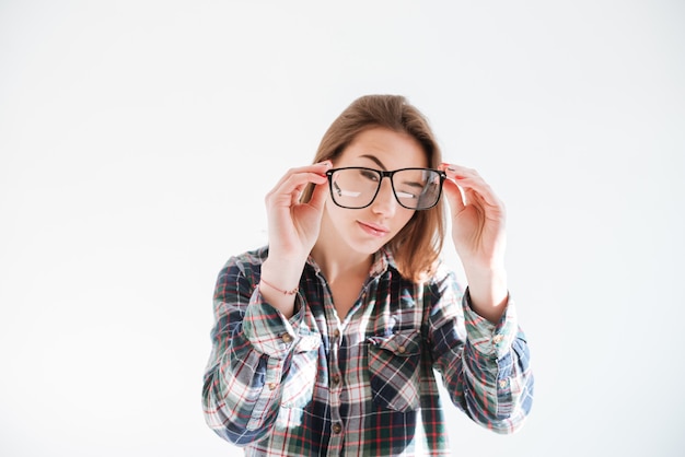 Konzentrierte Frau hält Brille und posiert