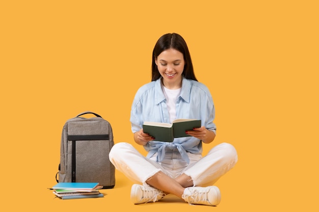 Konzentrierte Frau liest ein Buch auf gelbem Hintergrund