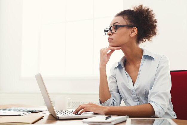 Konzentrierte Geschäftsfrau, die im Büro an Laptop arbeitet. Geschäftsfrau, die an ihrem Arbeitsplatz sitzt, Kopienraum