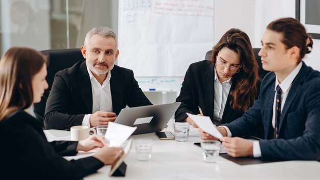 Konzentrierte Geschäftsleute diskutieren Dokumente. Eine Gruppe von Geschäftspartnern liest die Vertragsvereinbarung im Besprechungsraum