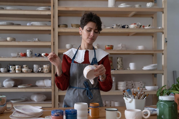 Konzentrierte junge Frau arbeitet als professionelle Töpferin im Atelier