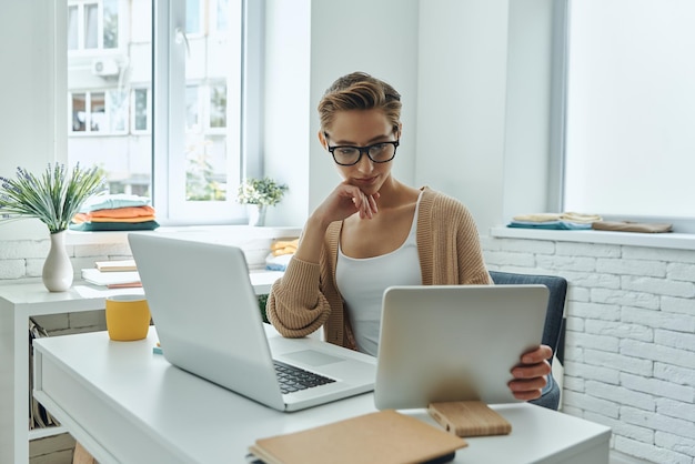 Konzentrierte junge Frau, die Technologien verwendet, während sie im Kreativbüro arbeitet