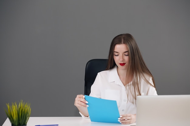 Konzentrierte kluge junge Geschäftsfrau, die ihren Computer im Büro benutzt