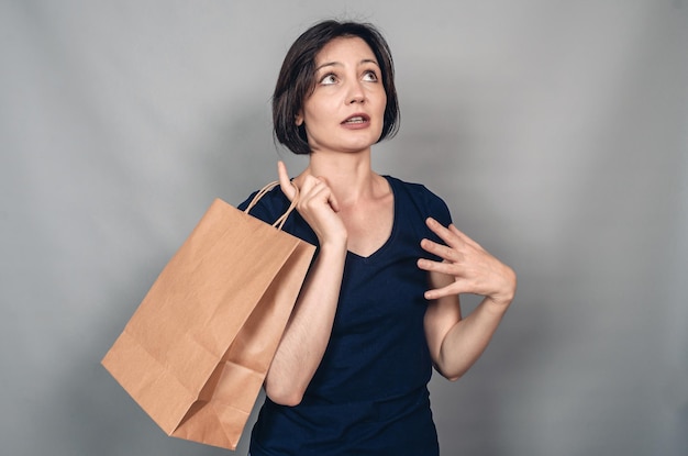 Konzentrierte nachdenkliche Frau vor dem Einkauf Papiertüte in der Hand