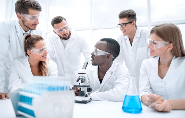 Konzentrierte und seriöse Chemikerinnen und Chemiker in Laborkitteln und Schutzbrillen beim Experimentieren