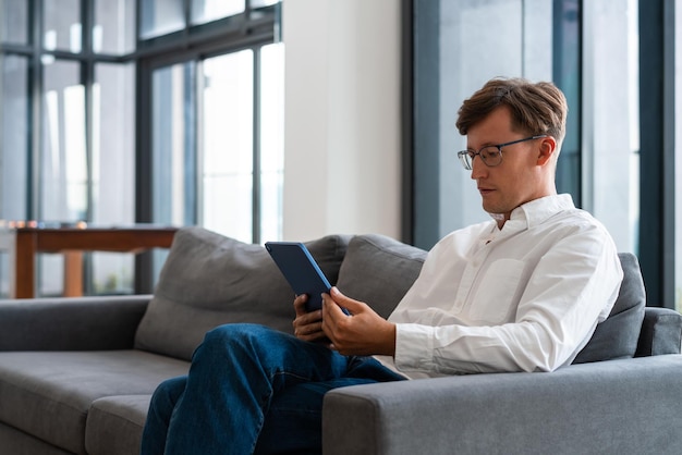 Konzentrierter Geschäftsmann mit Tablet auf einem Sofa sitzend