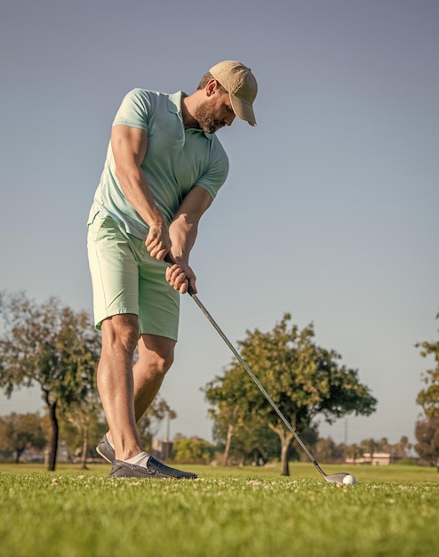 Konzentrierter Golfspieler in der Kappe mit dem Golfclubgolfen