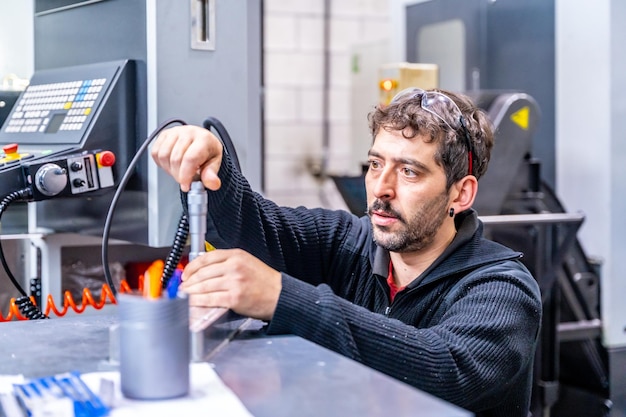 Konzentrierter Ingenieur hockt und repariert ein Stück Metall in einer modernen CNC-Fabrik