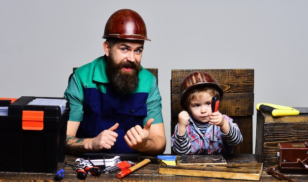Konzentrierter Junge mit Vater, der zusammen repariert Vater lehrt kleinen Sohn, Werkzeuge zu benutzen. Vaterschaft, Reparatur, Hilfskonzept.