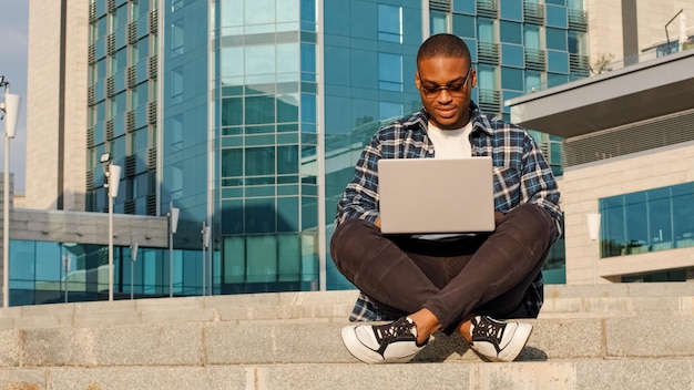 Konzentrierter junger Geschäftsmann, afrikanisch-amerikanischer Freiberufler, Student mit Sonnenbrille sitzt