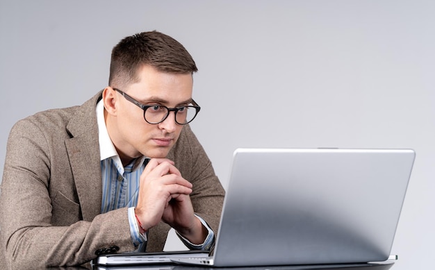 Konzentrierter junger Mann, der im Büro am Laptop arbeitet