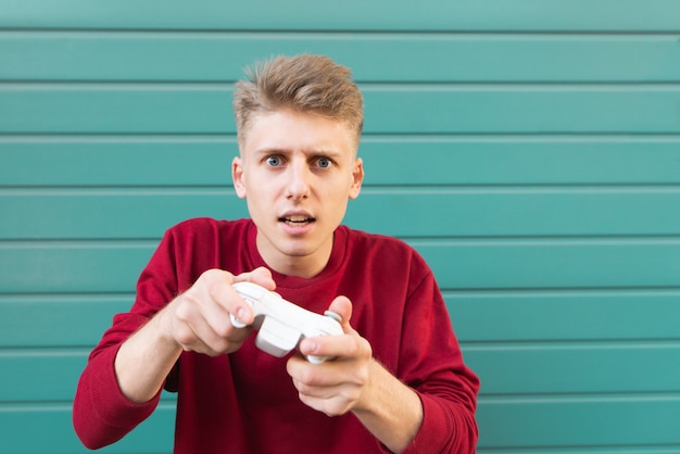 Konzentrierter junger Spieler mit Joystick in den Händen auf Türkis.