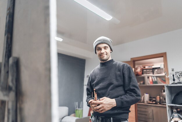 Konzentrierter Mann, der in einem Studio nahe der Leinwand steht und ein Bild malt