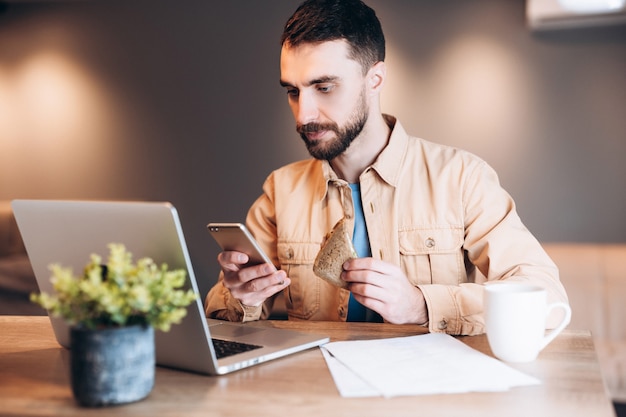 Konzentrierter Mann mit Telefon und Laptop