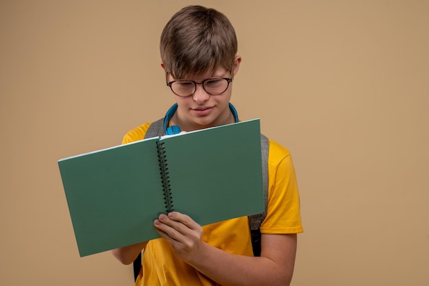 Konzentrierter Schüler mit Brille, der in sein Notizbuch schreibt