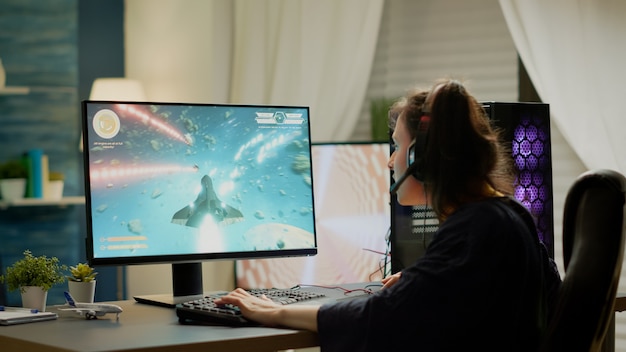 Konzentrierter Spieler, der auf einem Gaming-Stuhl sitzt und Online-Weltraum-Shooter-Videospiele mit dem RGB-Schlüsselwort spielt. Professionelles Profi-Cyber-Streaming von Online-Videospielen neue Grafiken mit leistungsstarkem PC