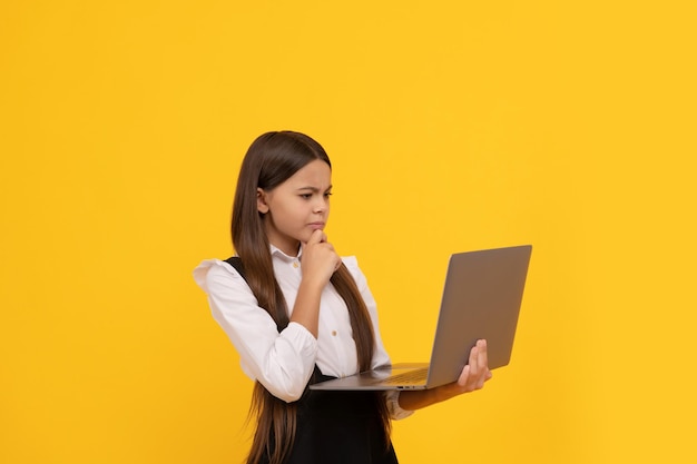 Konzentriertes ernsthaftes Teenager-Mädchen in Schuluniform studiert Laptop-Wissen