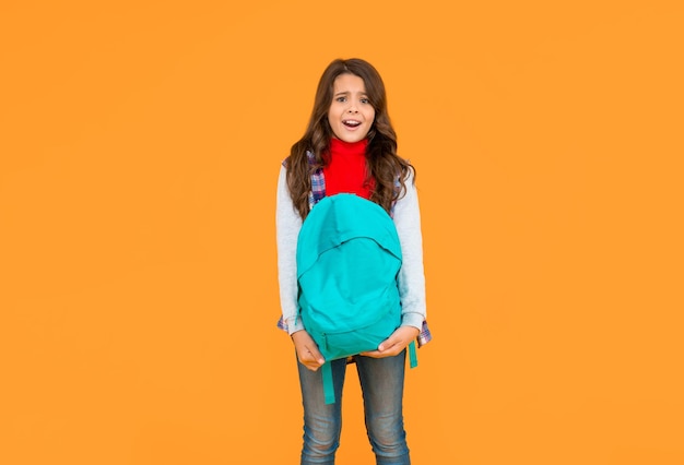 Konzept der Bildung Kind in Freizeitkleidung auf gelbem Hintergrund 1. September glückliches Kind aus der Kindheit mit Schultasche verwirrt Teenager-Mädchen tragen Rucksack zurück zum Tag des Wissens in der Schule