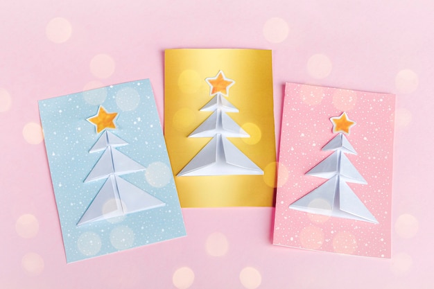 Konzept der DIY- und Kinderkreativität, Origami. Machen Sie blaue, rosa, goldene Grußkarten mit Weihnachtsbaum Origami