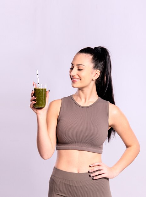 Konzept der Entgiftung, gesunden Ernährung und Fitness. Junge Frau, die ein Glas mit grünem Smoothie hält.