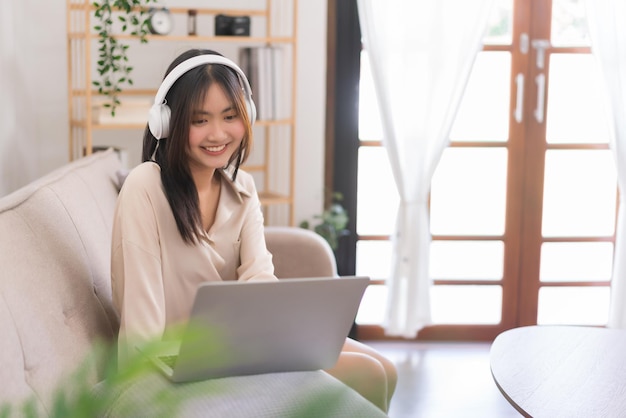 Konzept der Entspannung zu Hause Asiatische Frau hört Musik und plaudert mit Freund auf Laptop