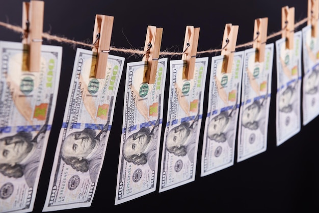 Konzept der Geldwäsche von hundert Rechnungen, die an einer Schnur vor grauem Hintergrund hängen