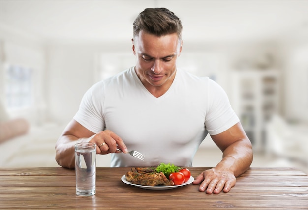 Konzept der gesunden Ernährung, muskulöser Mann, der Fleisch und Gemüse isst