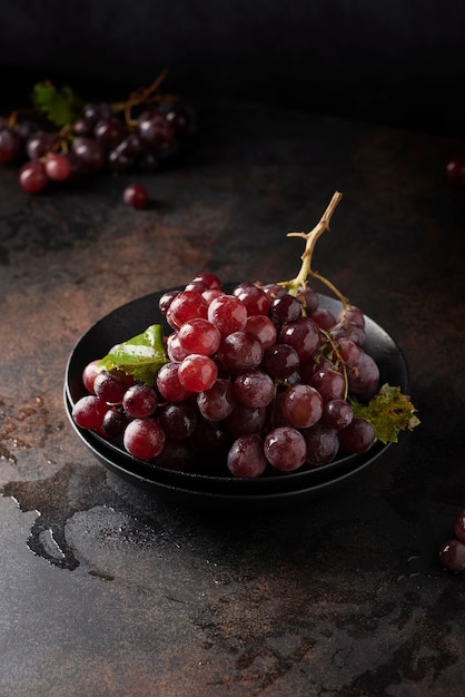 Konzept der gesunden vegetarischen Nahrung. Rote Trauben auf dem schwarzen Tisch, selektives Fokusbild