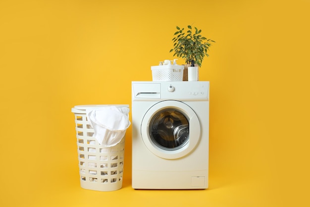 Konzept der Hausarbeit mit Waschmaschine auf gelbem Hintergrund